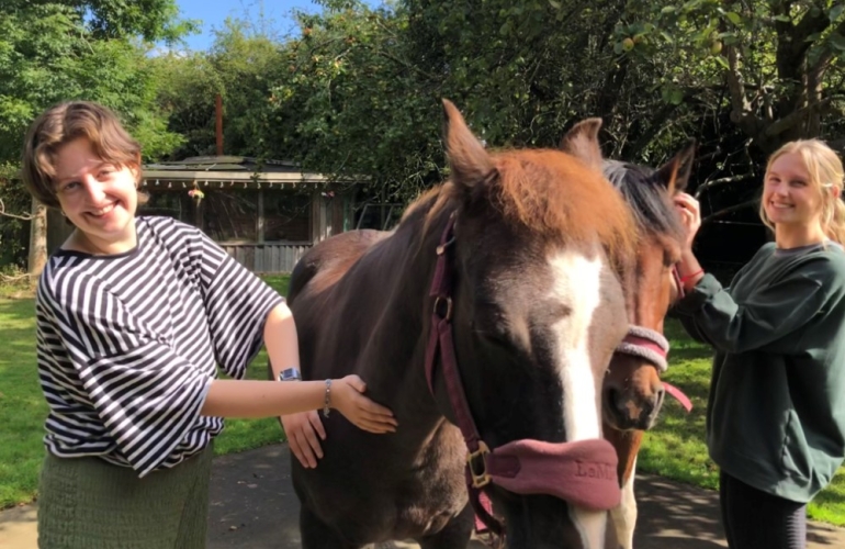 Two girls stroking a horse